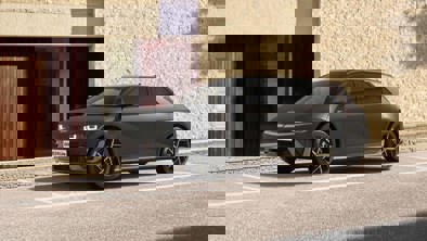 En sort SUV parkeret på en gade foran en struktureret beige stenmur med synlige digitale forvrængninger.