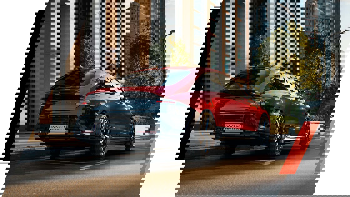 Et glitchet, forvrænget billede af en sort og en rød bil, der kører på en gade i byen med moderne bygninger i baggrunden.