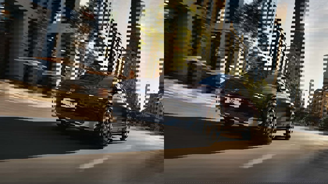 En sort bil kører på en bygade med høje bygninger, men billedet virker forvrænget og pixeleret.