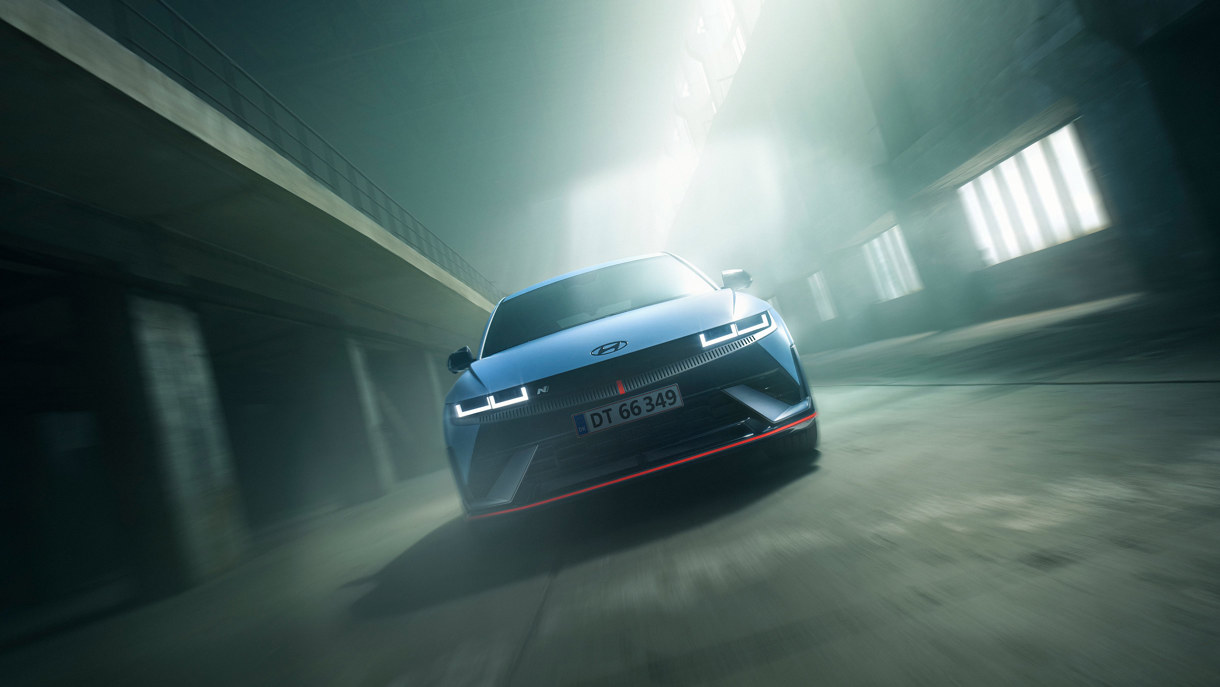 En blå Hyundai er fotograferet forfra i et industrielt rum med blødt lys, der strømmer ind gennem høje vinduer.