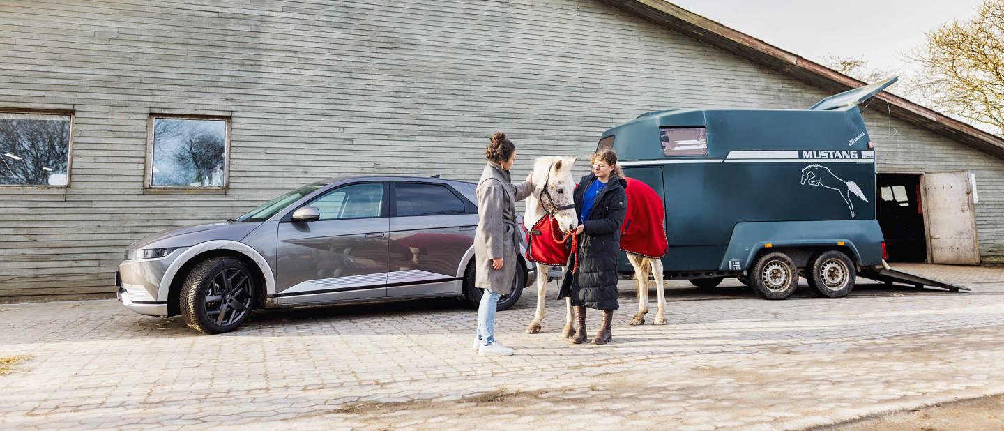 Mor og datter med hest foran Hyundai IONIQ 5 med hestetrailer på anhængertrækket