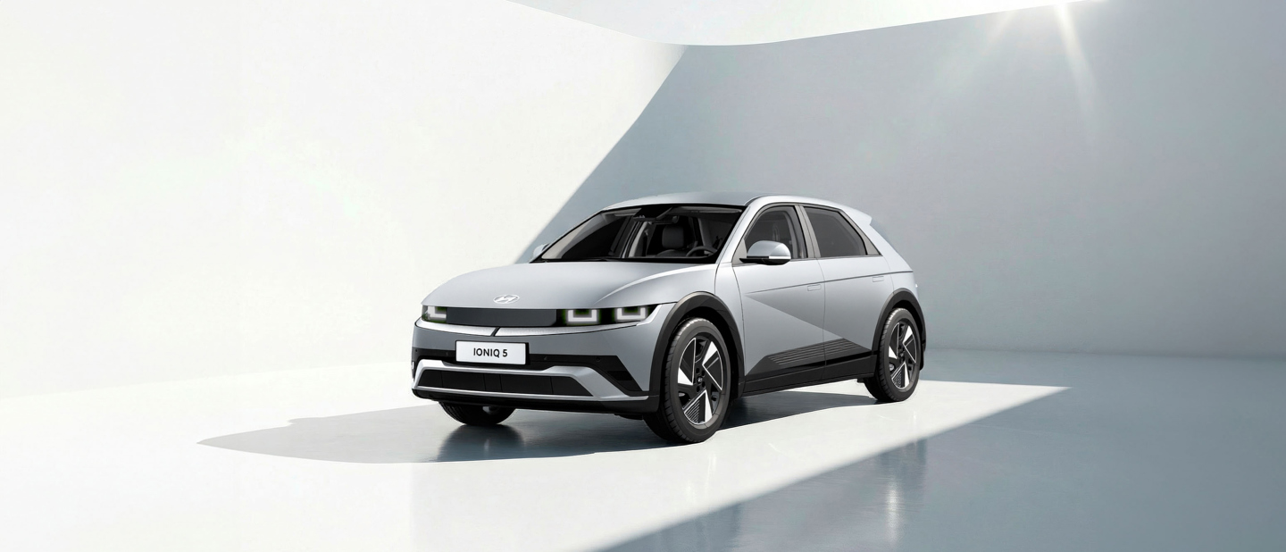 En sølvfarvet Hyundai IONIQ 5 elbil er parkeret i et lyst, minimalistisk hvidt rum, hvor sollyset strømmer ind.