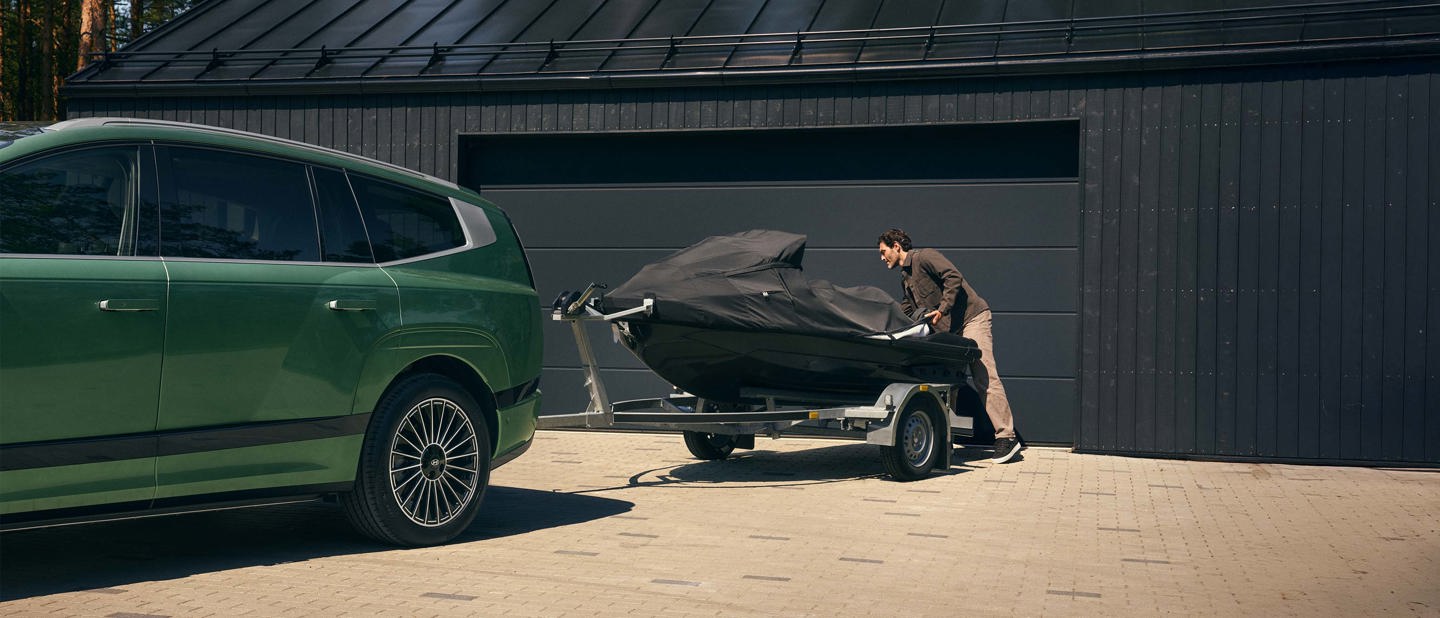 En bil er parkeret uden for et vindue med lukkede persienner, som delvist skygger for udsynet til både gaden og bilen.