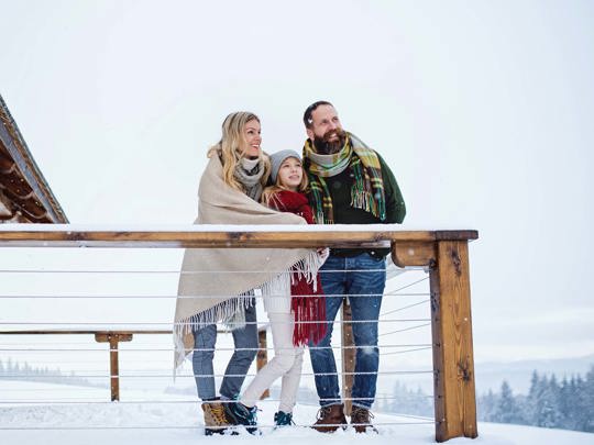 Familie står på terrasse og kigger ud over snelandskab