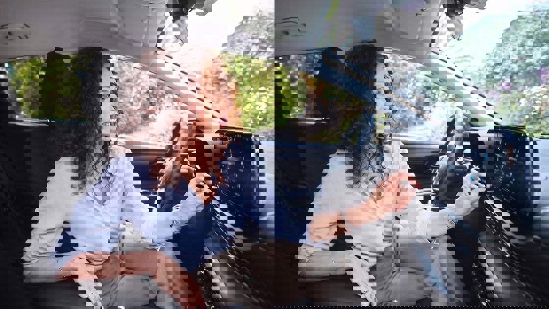 Kvinde skrurer op for musikken på skærmen i hendes Hyundai BAYON