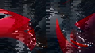 Udsigt til moderne bygningsinteriør med buede linjer og glasfacader, set gennem vandrette grøntonede persienner eller lameller.