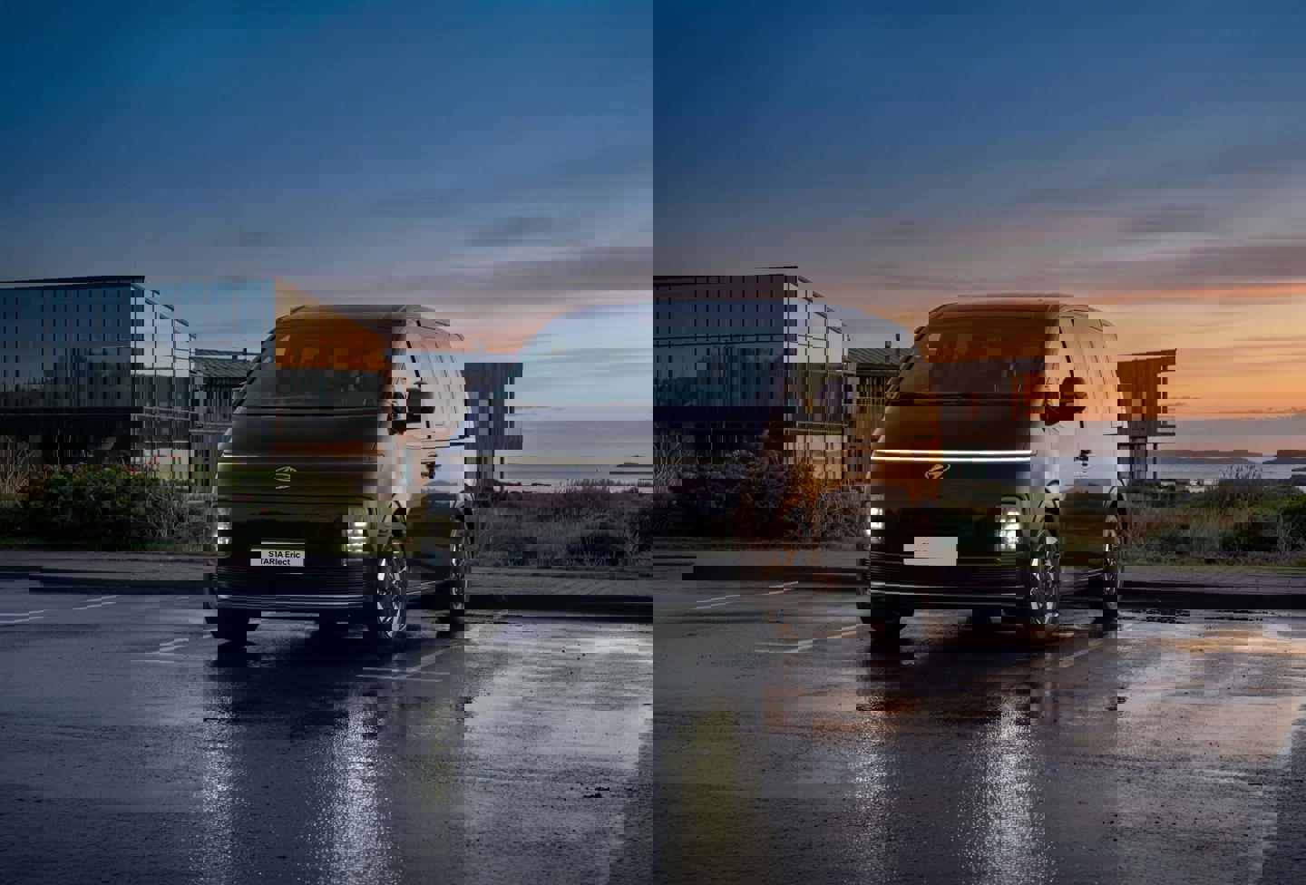 En sort varevogn på et vådt fortov foran moderne bygninger, hvor billedet er forvrænget af digitale fejl.