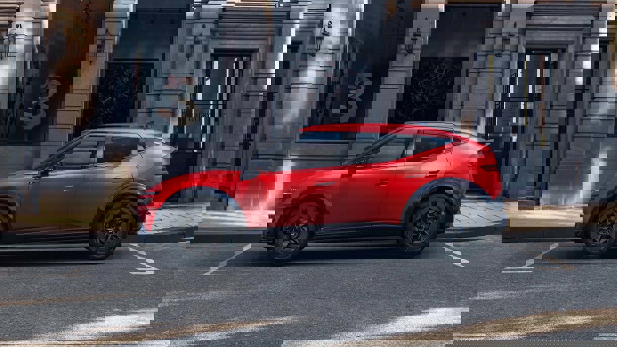 En hvid bil er parkeret på en gade i byen foran en murstensvæg med graffiti og hængende belysning i industriel stil.