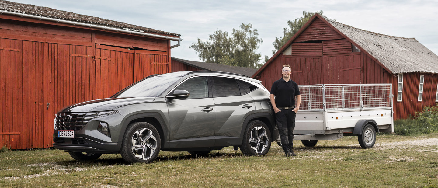 Hyundai-ejer ved siden af sin Hyundai TUCSON Plug-in Hybrid med trailer på anhængertrækket