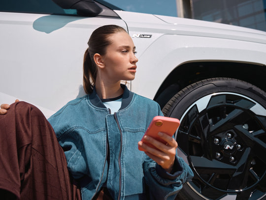 Kvinde holder sin mobil foran en Hyundai