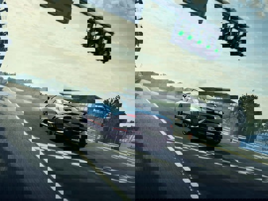 Et forvrænget, glitchy billede af en motorcykel, der kører på en bygade med slørede køretøjer og trafiksignaler.